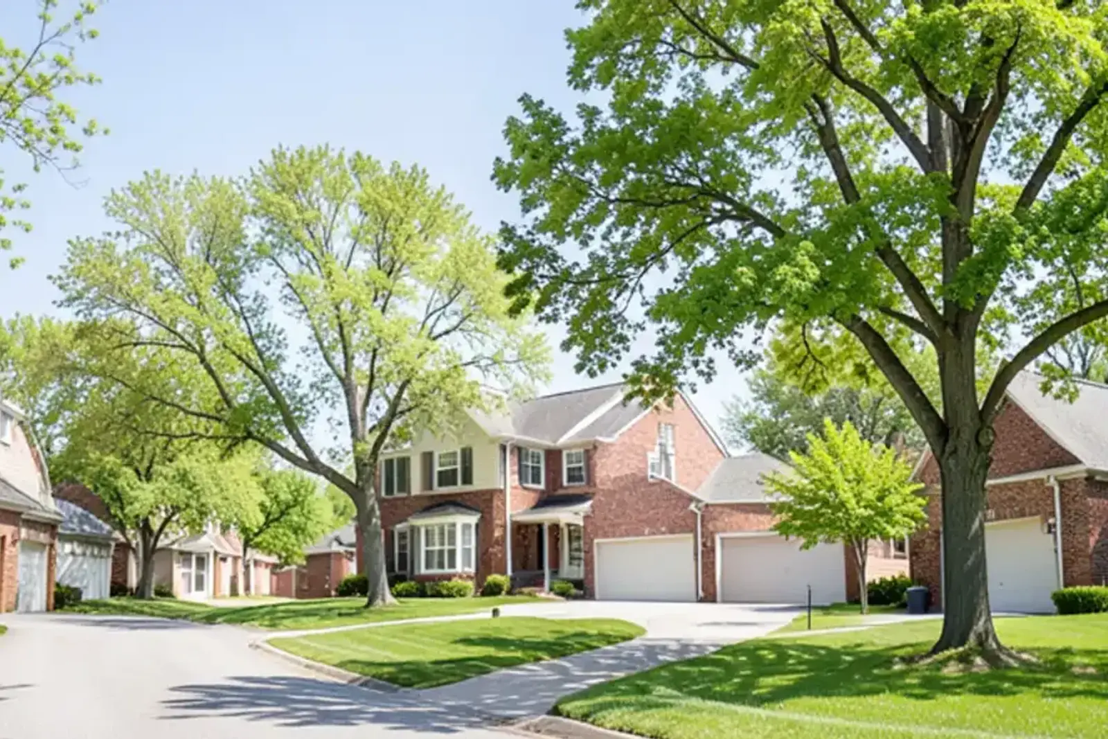 Two-story 1970s brick colonial homes on a curving subdivision street