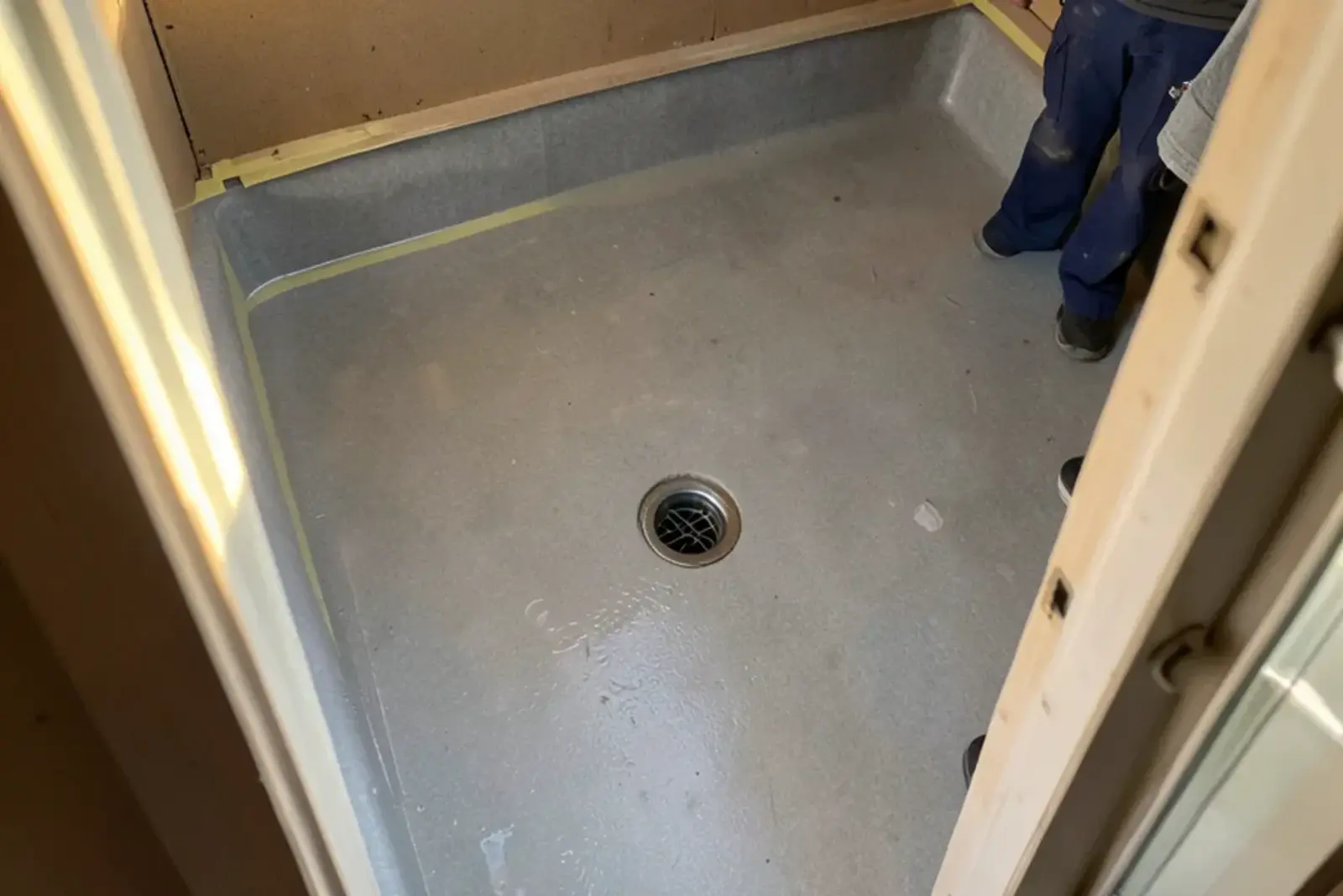 Shower pan liner filled with water around a clamped drain during a test before tile goes down