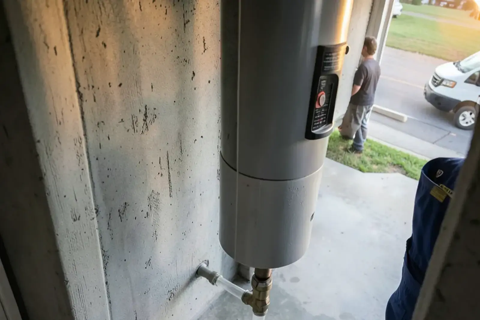 Clear condensate tube running from a tankless water heater down a basement wall to a floor drain